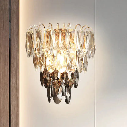 A modern brass and crystal tiered wall sconce chandelier with cascading clear gold and smoky crystal droplets