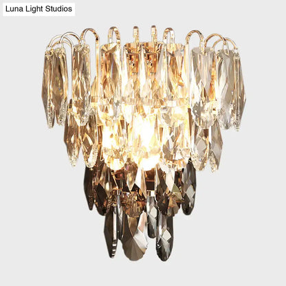 Modern brass and crystal tiered wall sconce bedroom chandelier with cascading golden and clear faceted glass pieces and warm light