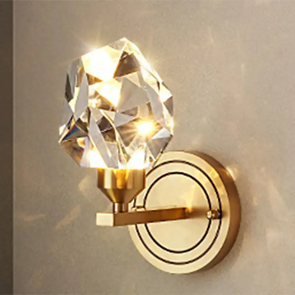 A faceted crystal globe wall mount light with modern brass concentric circular detailing for living room decor