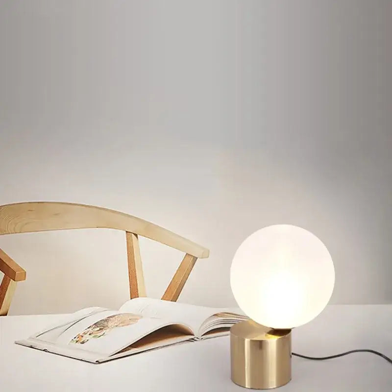 Modern brass and decorbites glass circular table lamp with frosted white globe on cylindrical brass base for bedroom