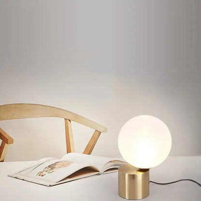 Modern brass and decorbites glass circular table lamp with frosted white globe on cylindrical brass base for bedroom