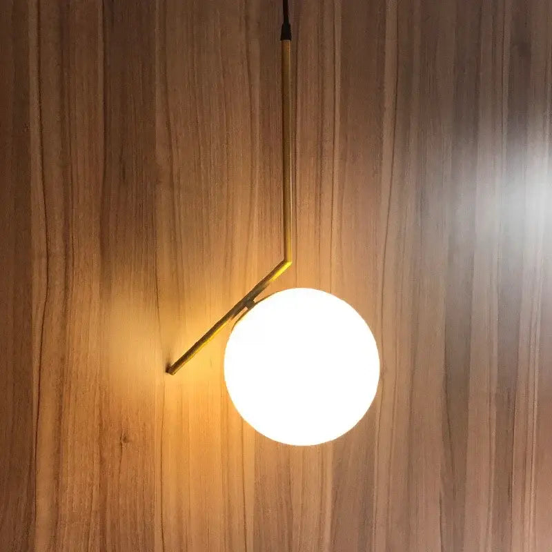 Modern brass and frosted glass ball pendant light fixture with gold metal frame and white spherical shade for dining room decorbites glass ball