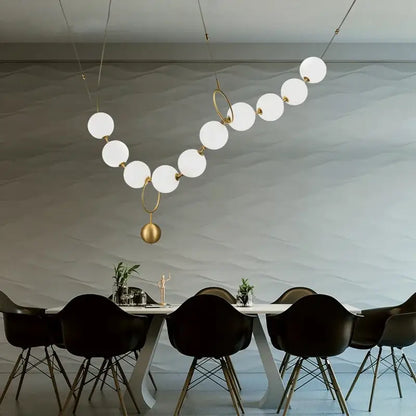 Modern brass and glass ball pendant light with white spherical bulbs and gold-toned rings for dining room decorbites glass ball