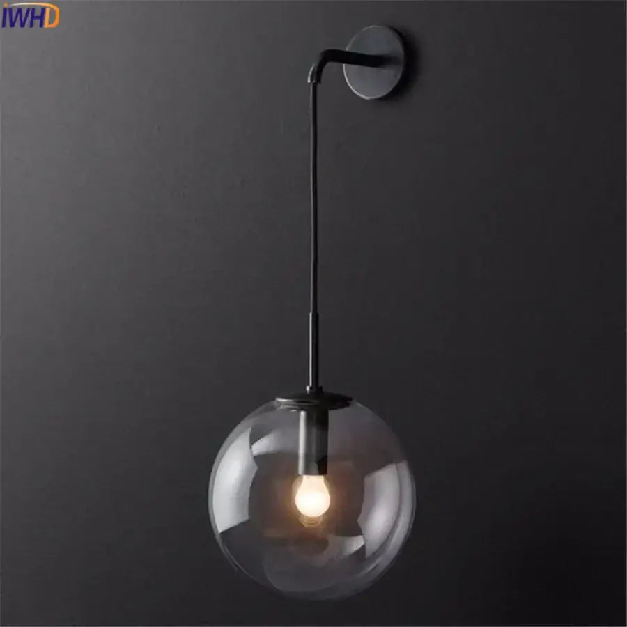 Modern black metal wall lamp with clear glass ball housing an exposed bulb for elegant decorbites glass ball lighting
