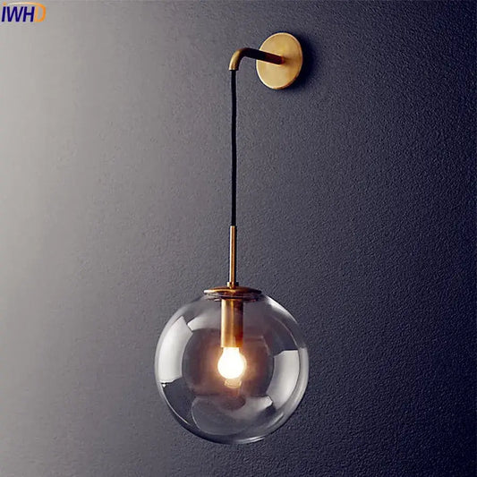 A sleek modern brass and glass ball wall lamp with a clear globe and black cord for bathroom decorbites glass ball