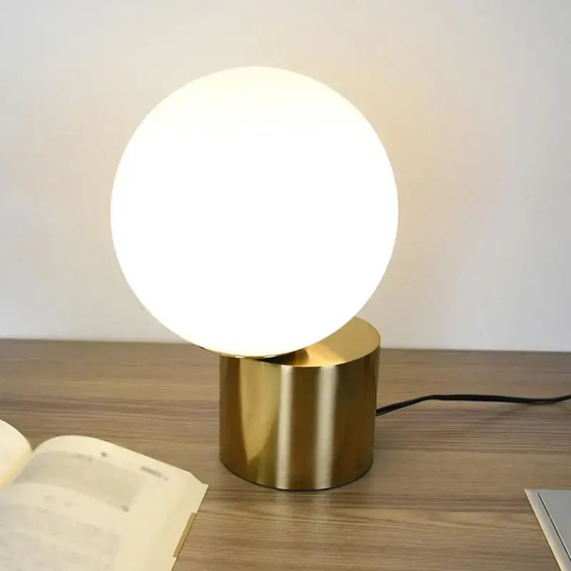 Modern brass and glass desk lamp with a glowing spherical shade ideal for bedroom decorbites glass desk lighting