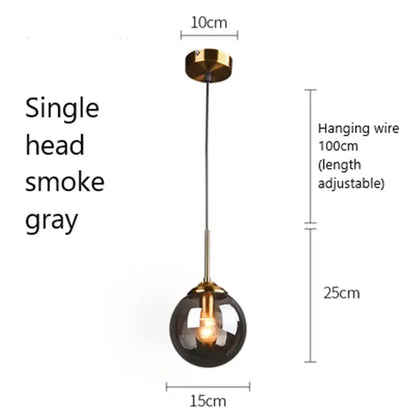 A sleek single-head glass pendant light with a smoke gray globe and gold-toned brass accents for kitchen use