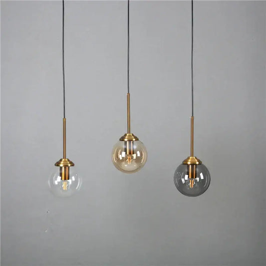 Modern brass and glass pendant lights with clear, amber, and smoked gray glass pendant shades for kitchen dining room