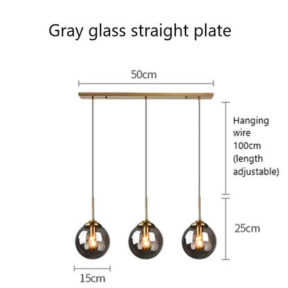 Modern brass and glass pendant lights featuring three gray glass pendant spheres suspended by adjustable wires for kitchen dining room