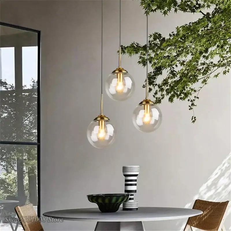 Three elegant modern brass and glass pendant lights with globe glass pendant shades for kitchen dining room lighting