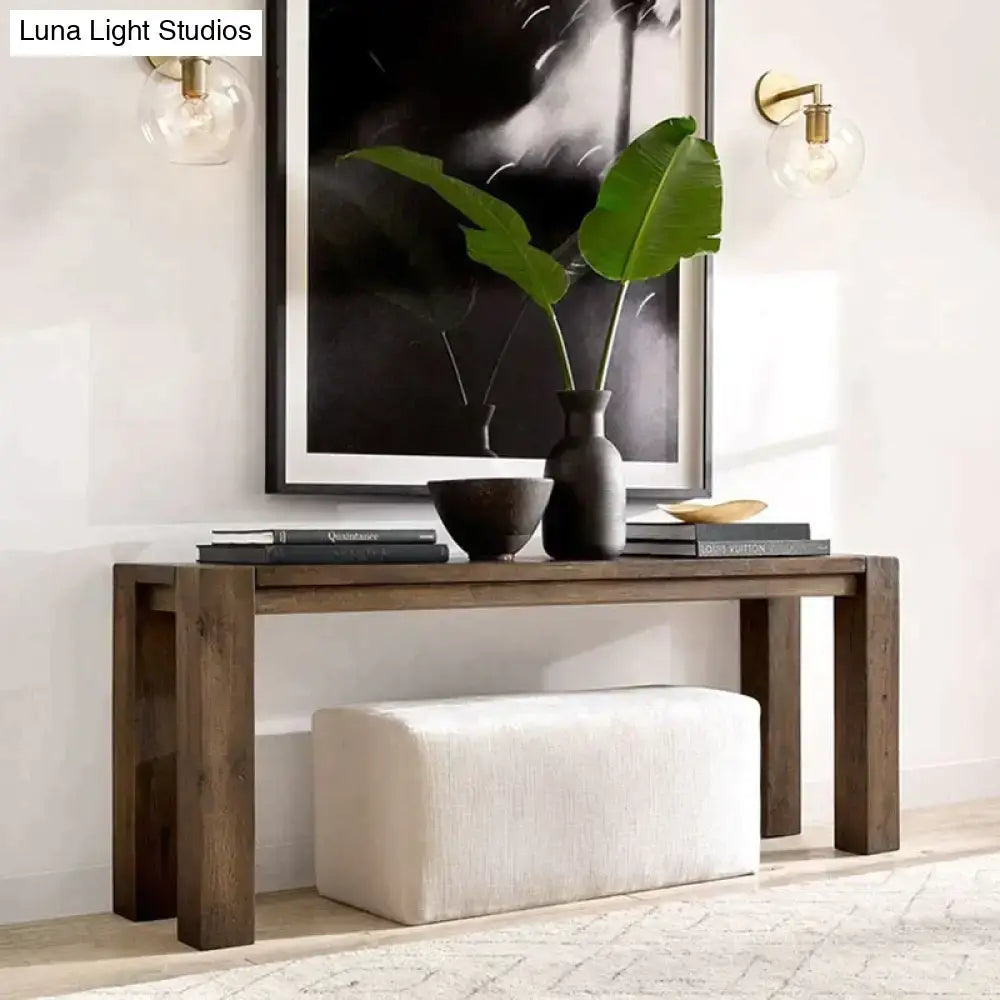 Modern brass and glass wall sconce bedroom light displayed above dark wood console table with black vase and green leaves