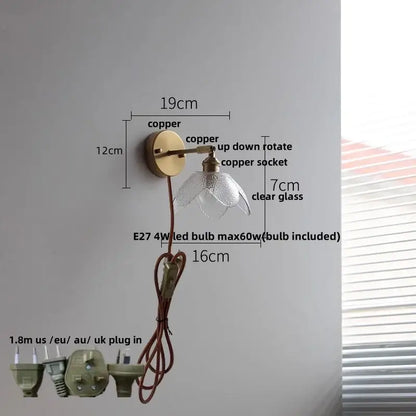 Modern brass and gray glass led wall sconce with copper adjustable arm and clear flower-shaped glass shade for bedroom lighting