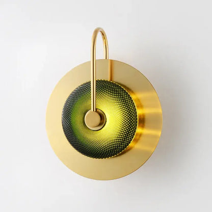 Modern brass metal wall art lamp with a gold-toned sconce and circular green and yellow glass diffuser for living room