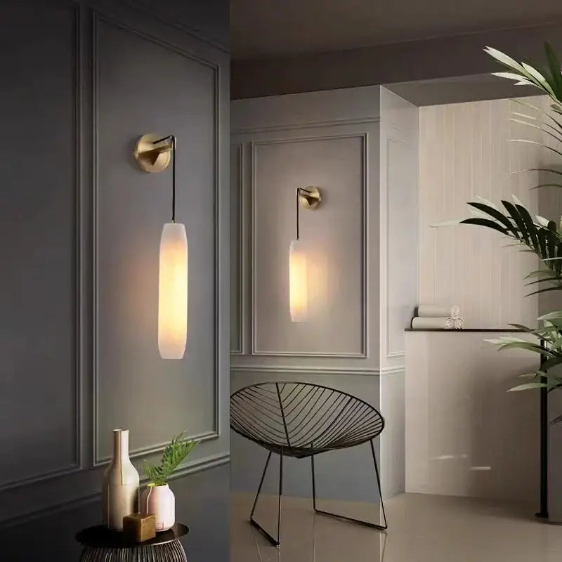 Modern brass and marble wall lamp with gold-toned decorbites cylindrical frosted glass shade emitting warm light