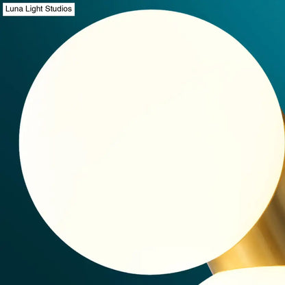 Modern brass and opal glass wall mount lamp with a sleek white spherical shade and polished gold-toned metal base