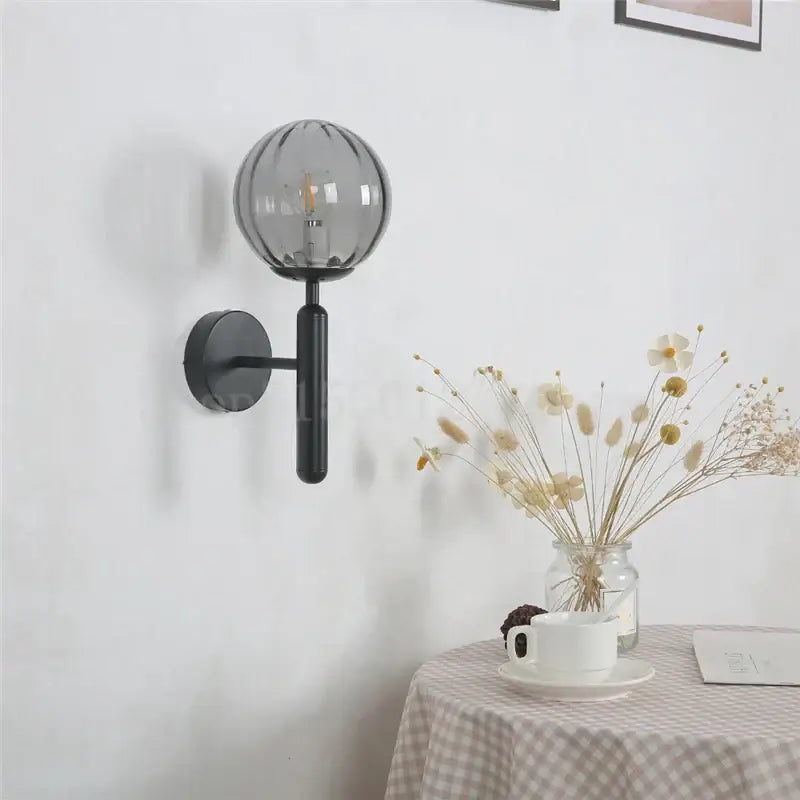 Modern brass and black metal wall sconce with textured smoked globe complementing decorbites blue glass balls decor