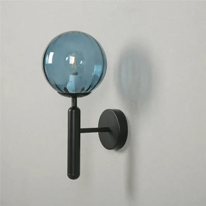 Modern brass and pink glass wall sconce with decorbites blue glass balls and black metal arm for bedroom lighting decor