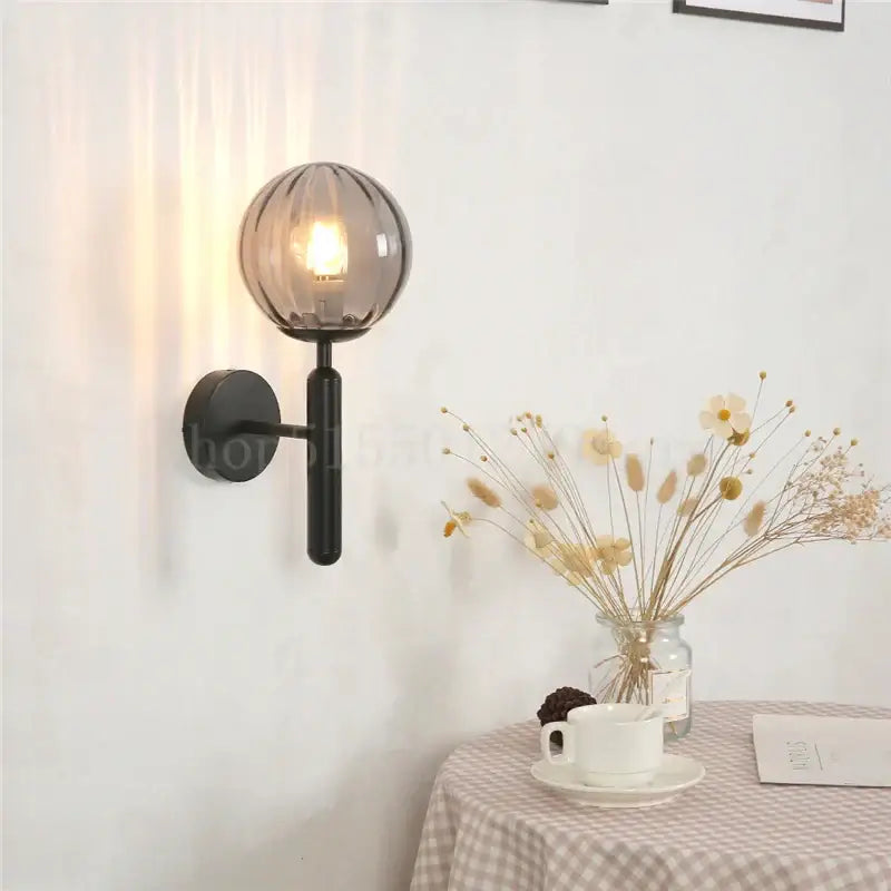 Modern black wall sconce with a smoked glass globe featuring brass accents for elegant bedroom decorbites blue glass use