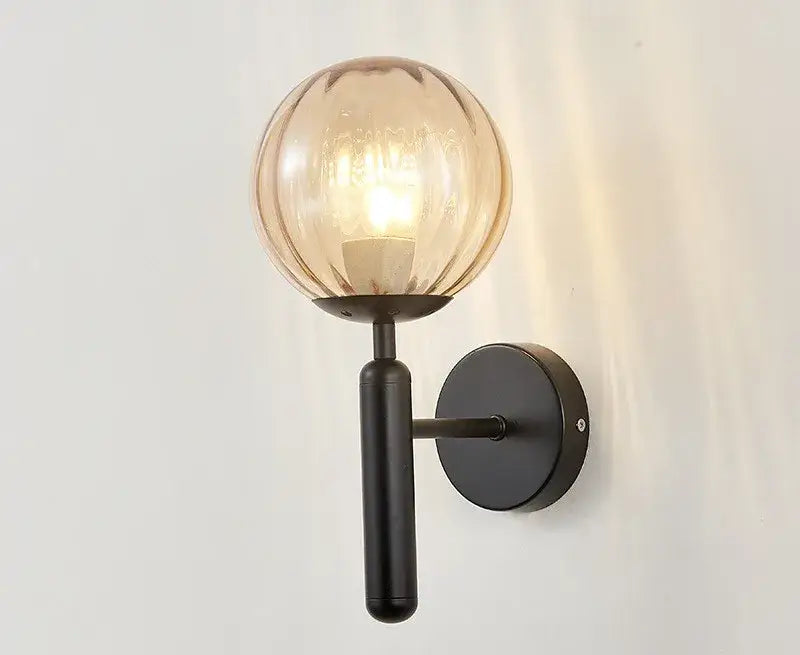 Modern black metal wall sconce with warm amber glass globe contrasting decorbites blue glass balls for bedroom lighting