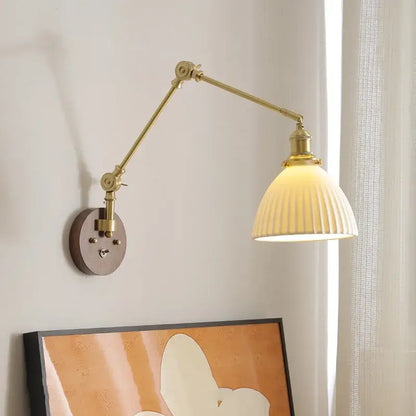 Modern brass and ribbed glass led wall lamp with adjustable brass arm and cream-colored shade for bedroom lighting