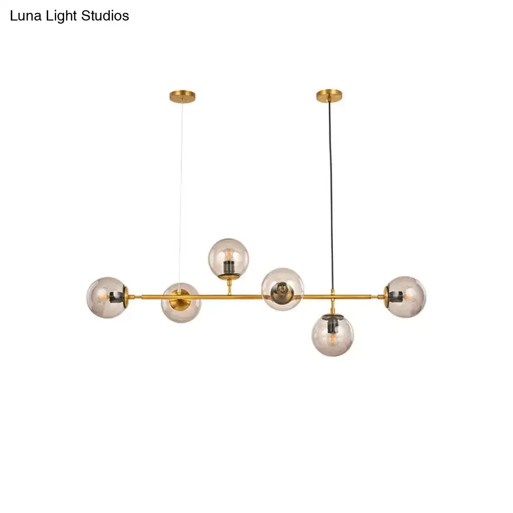 Gold-toned modern bubble chandelier lighting with six smoke gray glass globes suspended from horizontal bar