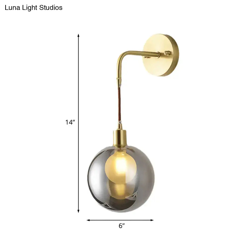 Modern brass and smoke gray glass corner wall light with brushed gold finish and curved arm for bedroom use