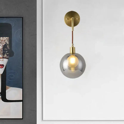 Modern brass and smoke gray glass corner wall light with smoked glass globe and exposed filament bulb bedroom sconce