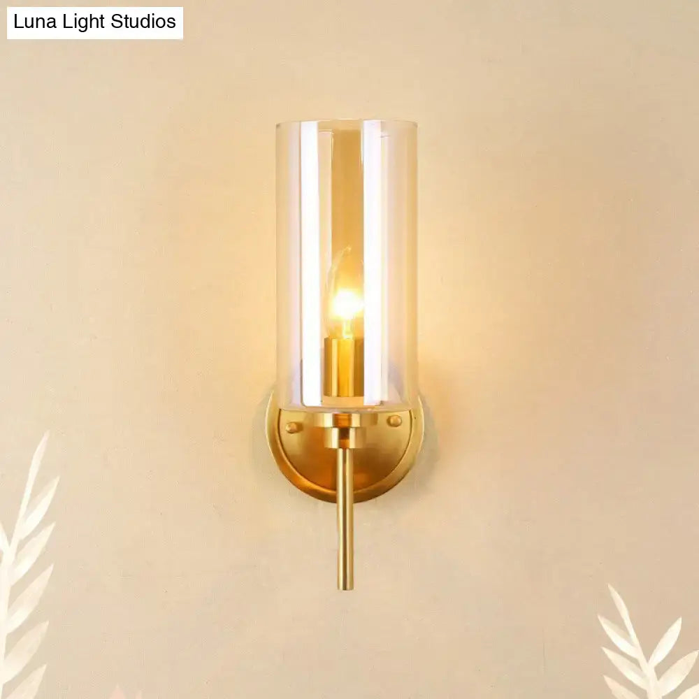 Modern brass and smoked glass wall sconce with gold tone, clear glass shade, and e26 bulb base for bedroom lighting