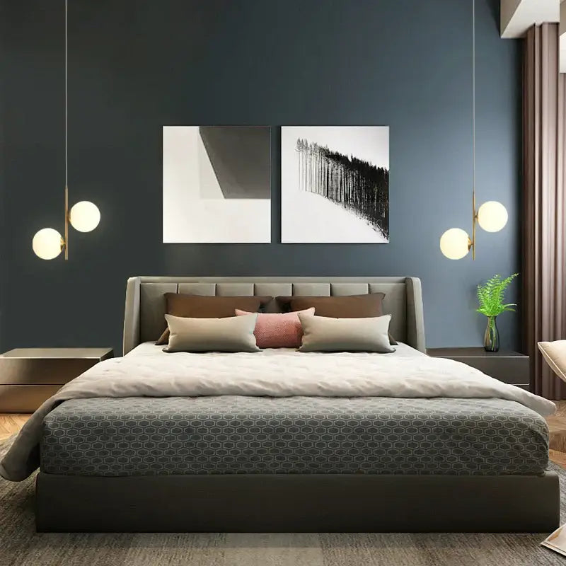 Modern gray upholstered bed with tufted headboard and geometric-patterned duvet beneath smoky gray glass globe pendant light