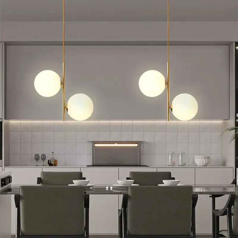 Modern brass pendant light with three smoky gray glass globe shades suspended by slender gold-toned rods for dining room