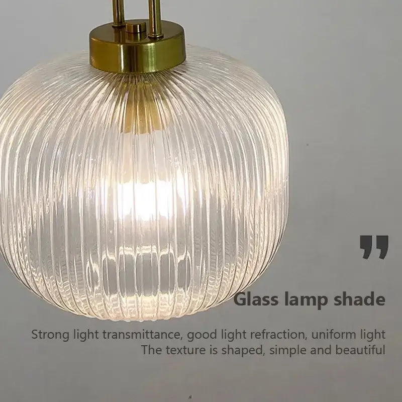 Modern brass and striped glass pendant light with a clear ribbed glass lampshade for dining room lighting
