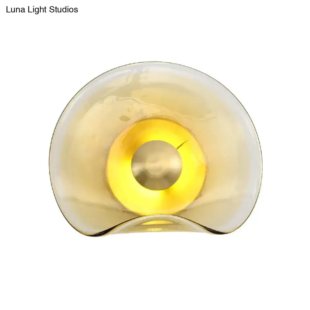 Modern brass and tan glass wall light fixture with translucent amber sconce and warm yellow illuminated center bulb wattage second gear
