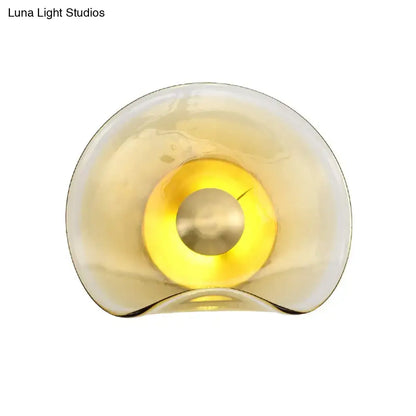 Modern brass and tan glass wall light fixture with translucent amber sconce and warm yellow illuminated center bulb wattage second gear