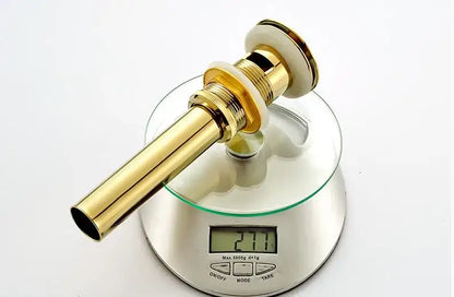 Modern gold-colored brass basin waste drain stopper with sleek cylindrical design and polished finish for bathroom sink