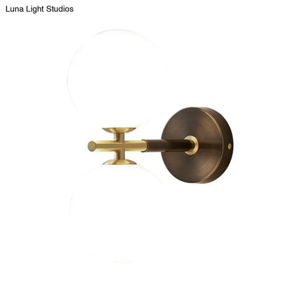 Modern brass wall sconce with white glass frosted globes and circular base for bedroom lighting