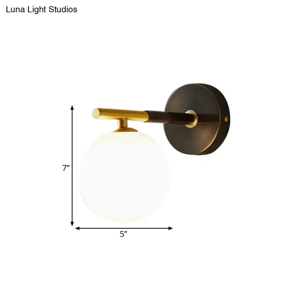 Modern brass and white glass wall sconce with matte black base and frosted globe for soft bedroom lighting