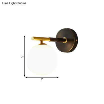 Modern brass and white glass wall sconce with matte black base and frosted globe for soft bedroom lighting