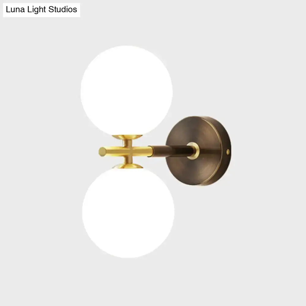 Modern brass wall sconce with two frosted white glass globe shades for bedroom lighting