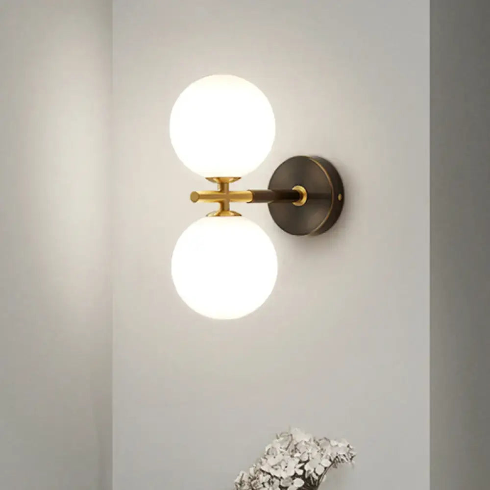 Modern brass wall sconce with two frosted white glass globe shades for bedroom lighting