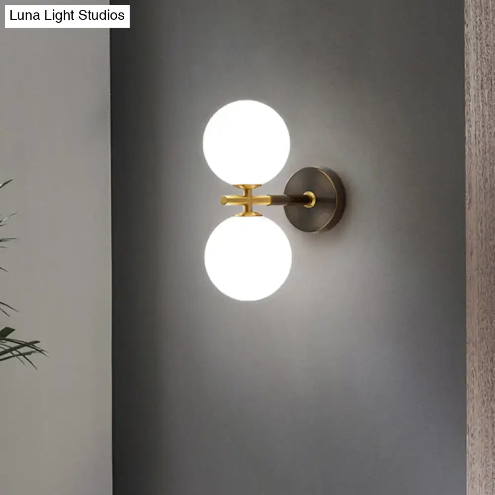 Modern brass and white glass wall sconce with two frosted glass globe shades for bedroom lighting