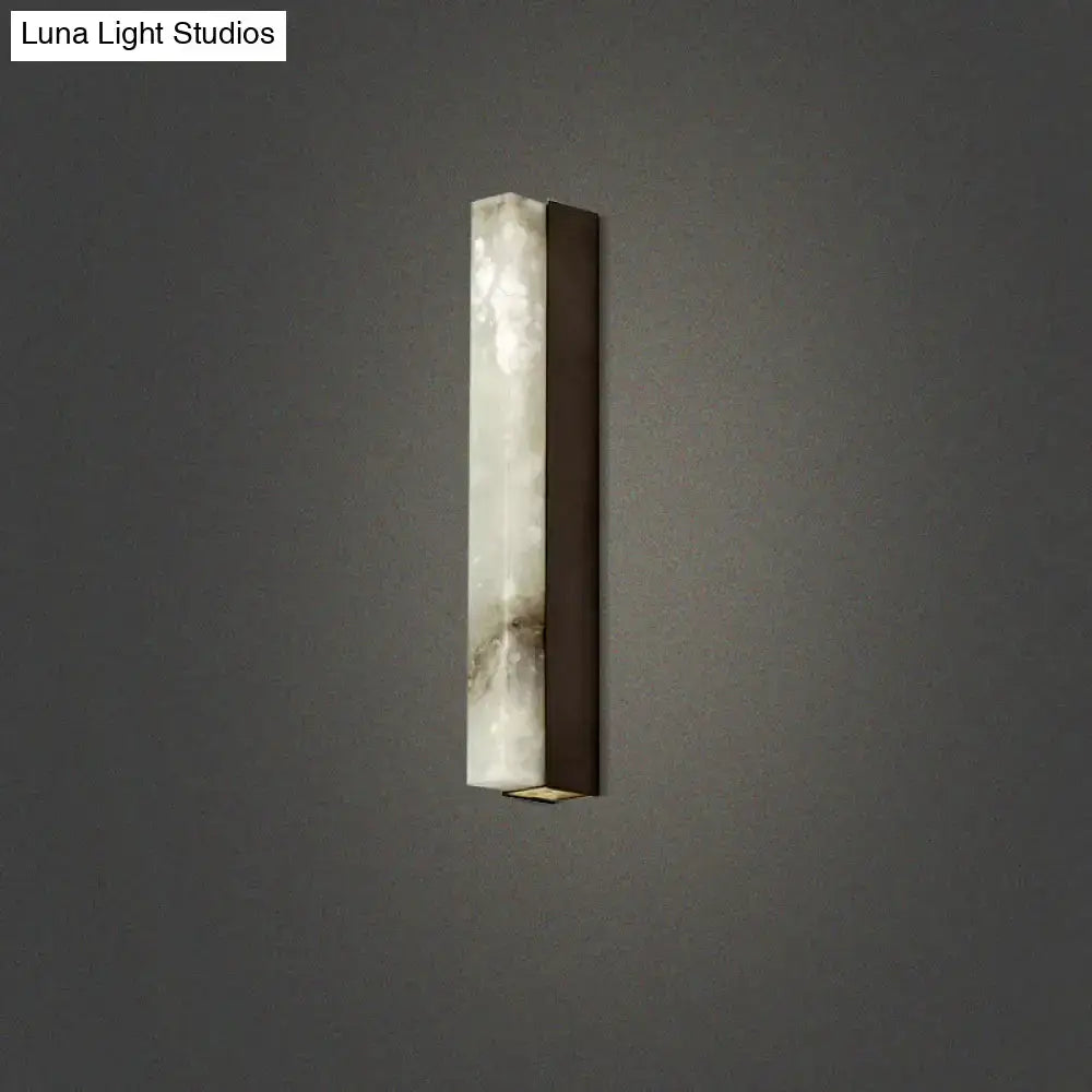 A sleek modern brass and white onyx wall lighting sconce with gray veined stone body for living room use