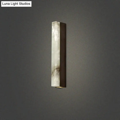 A sleek modern brass and white onyx wall lighting sconce with gray veined stone body for living room use