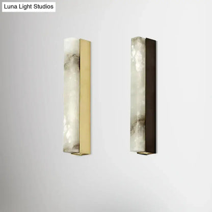Two sleek modern brass and white onyx wall lighting sconces with polished brass and dark bronze frames for living room use