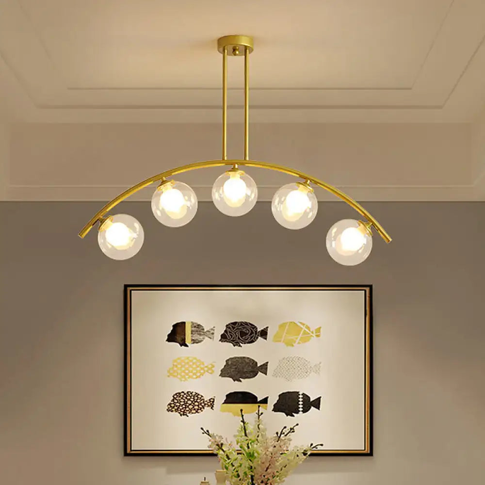 Decorbites modern glass orb island pendant light with five clear glass globes and brass arch arm for dining room