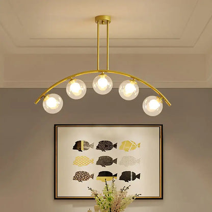 Decorbites modern glass orb island pendant light with five clear glass globes and brass arch arm for dining room
