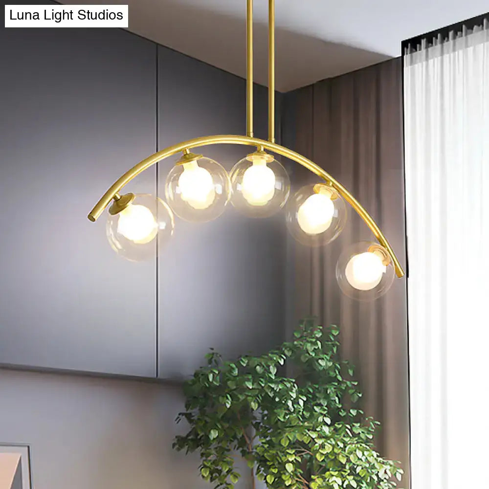 DecorBites modern glass orb pendant light with brass arch arm featuring five clear globe bulbs for dining room use