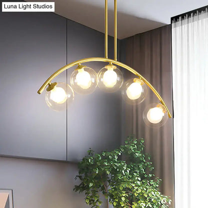 DecorBites modern glass orb pendant light with brass arch arm featuring five clear globe bulbs for dining room use