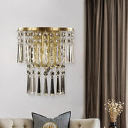 Modern brass wall sconce with gold tone and beveled glass crystal droplets for elegant corridor lighting