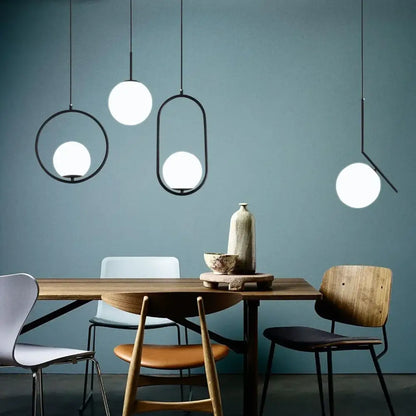 Modern brass and black glass ball pendant light with sleek black metal frames and glowing white glass ball shades