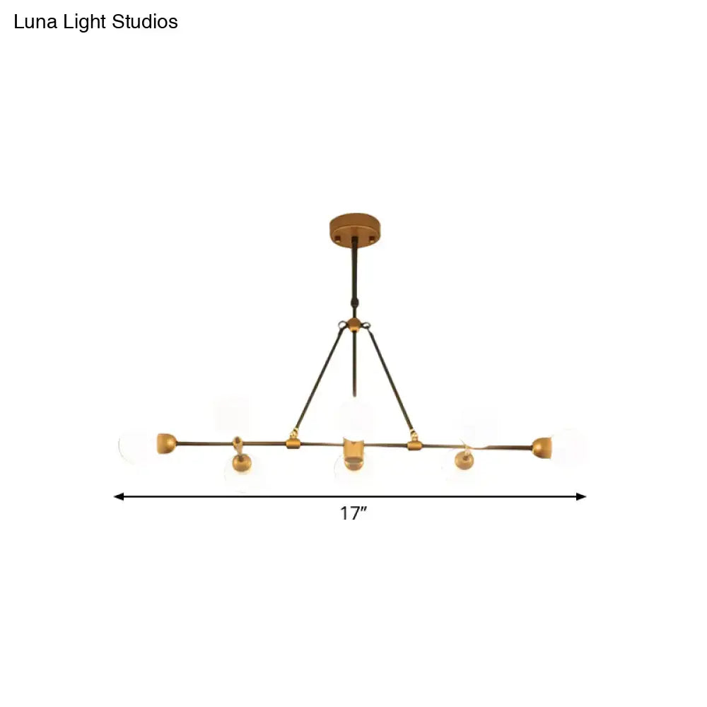 A modern brass finish dining room chandelier by Luna Light Studios with five orb glass shades and black metal accents